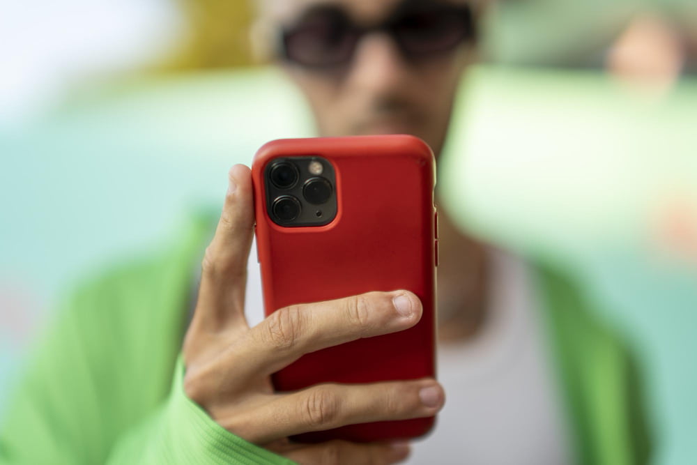 selective focus person looking smartphone red case