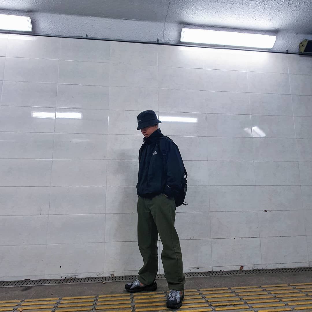 Homem de pé ao lado de uma parede com as mãos nos bolsos