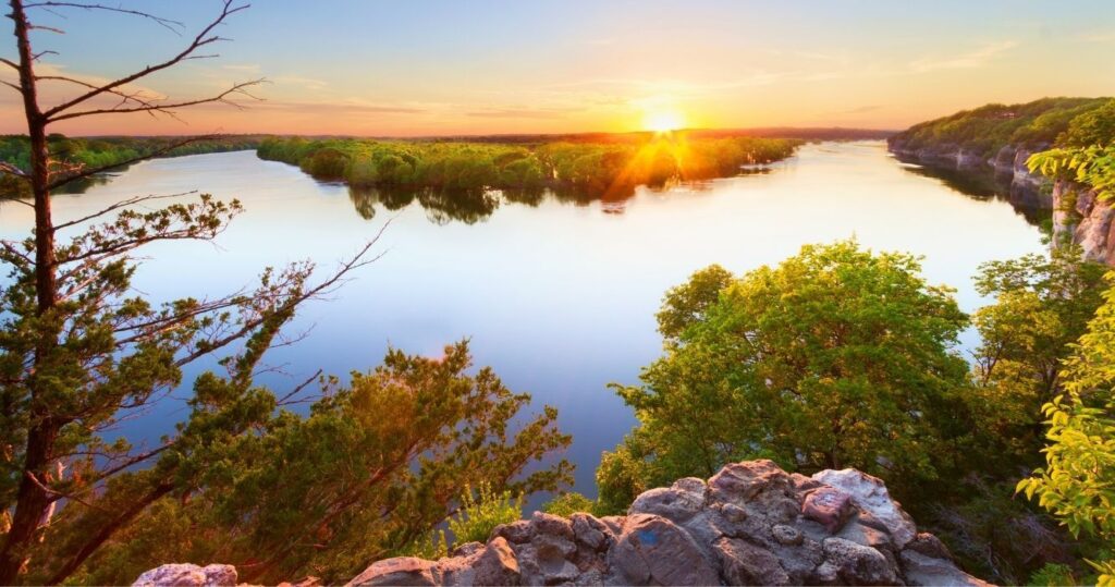 a sunset over the ozarks mountains and lake