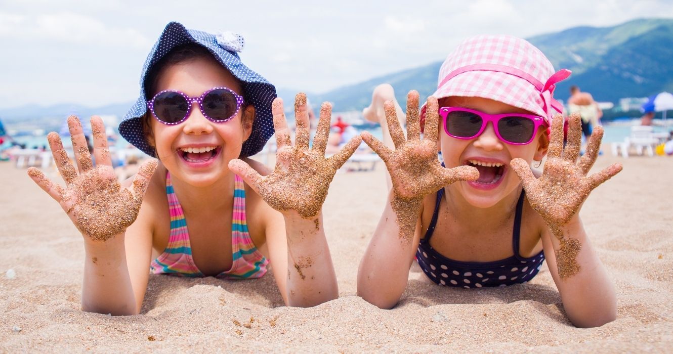 crianças com mãos de areia na praia