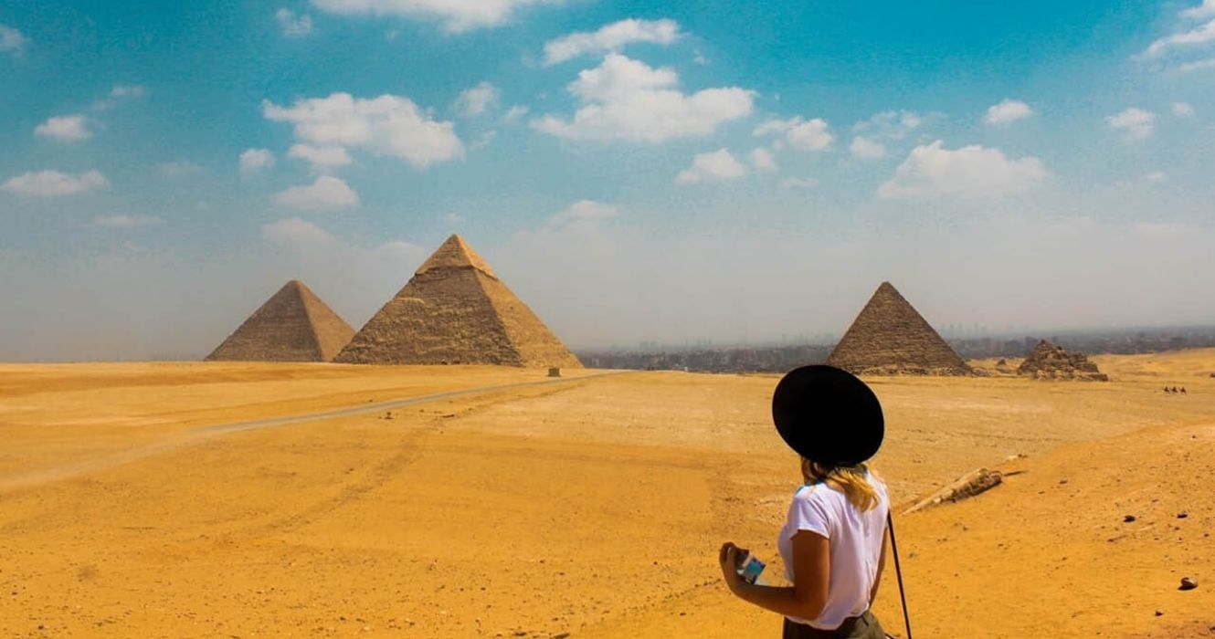 uma mulher tira uma foto em frente às pirâmides do egito
